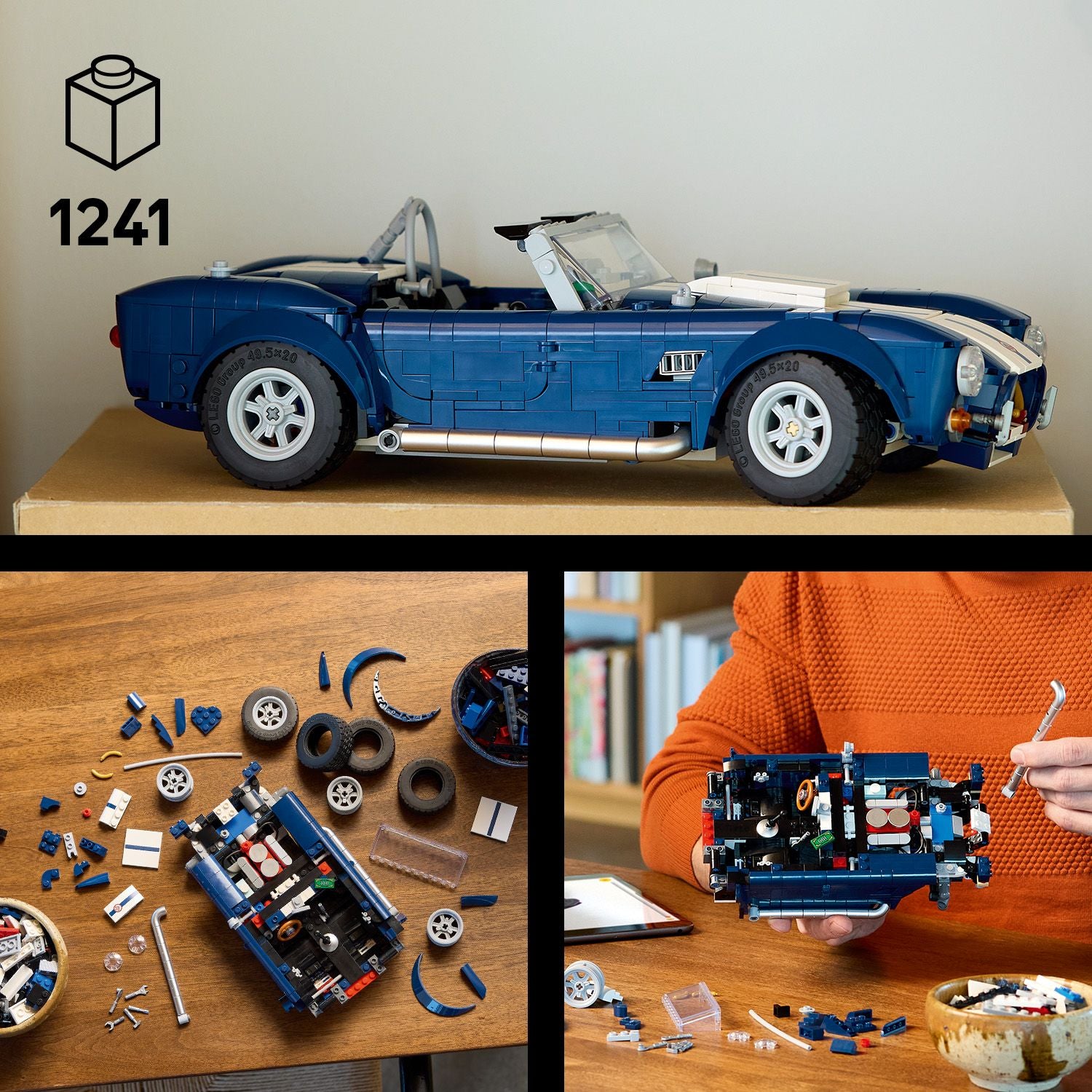 Seitliche Ansicht des blauen LEGO Shelby Cobra 427 Modells mit weißen Rennstreifen auf einem Karton. Darunter liegen zerlegte LEGO-Teile und Reifen auf einem Holztisch. Eine Person in orangefarbenem Pullover hält das teilweise zusammengebaute Modell mit Werkzeug in der Hand.