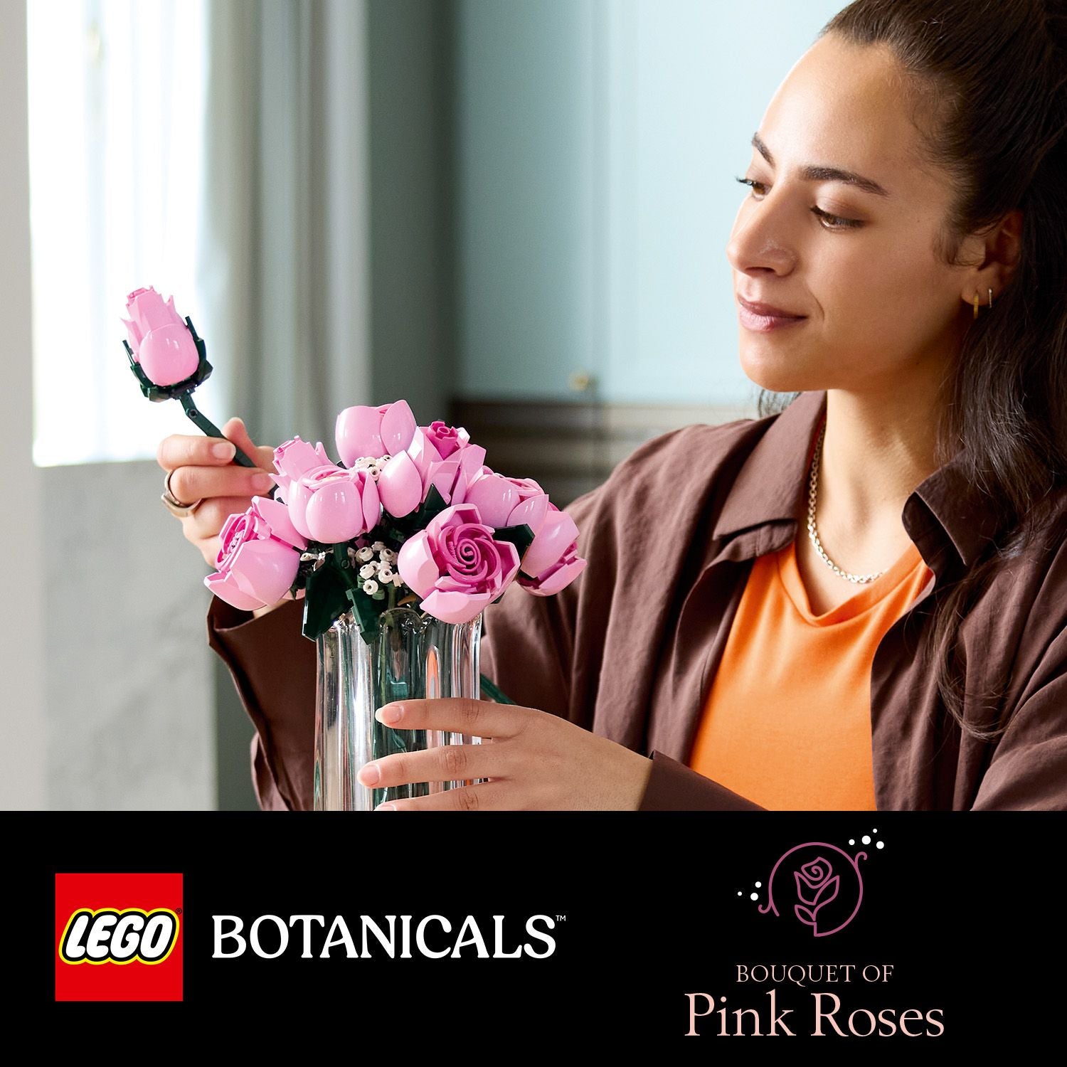 Person hält einen Glasvase mit einem Strauß aus rosa LEGO-Rosen und einer einzelnen LEGO-Rose in der Hand.