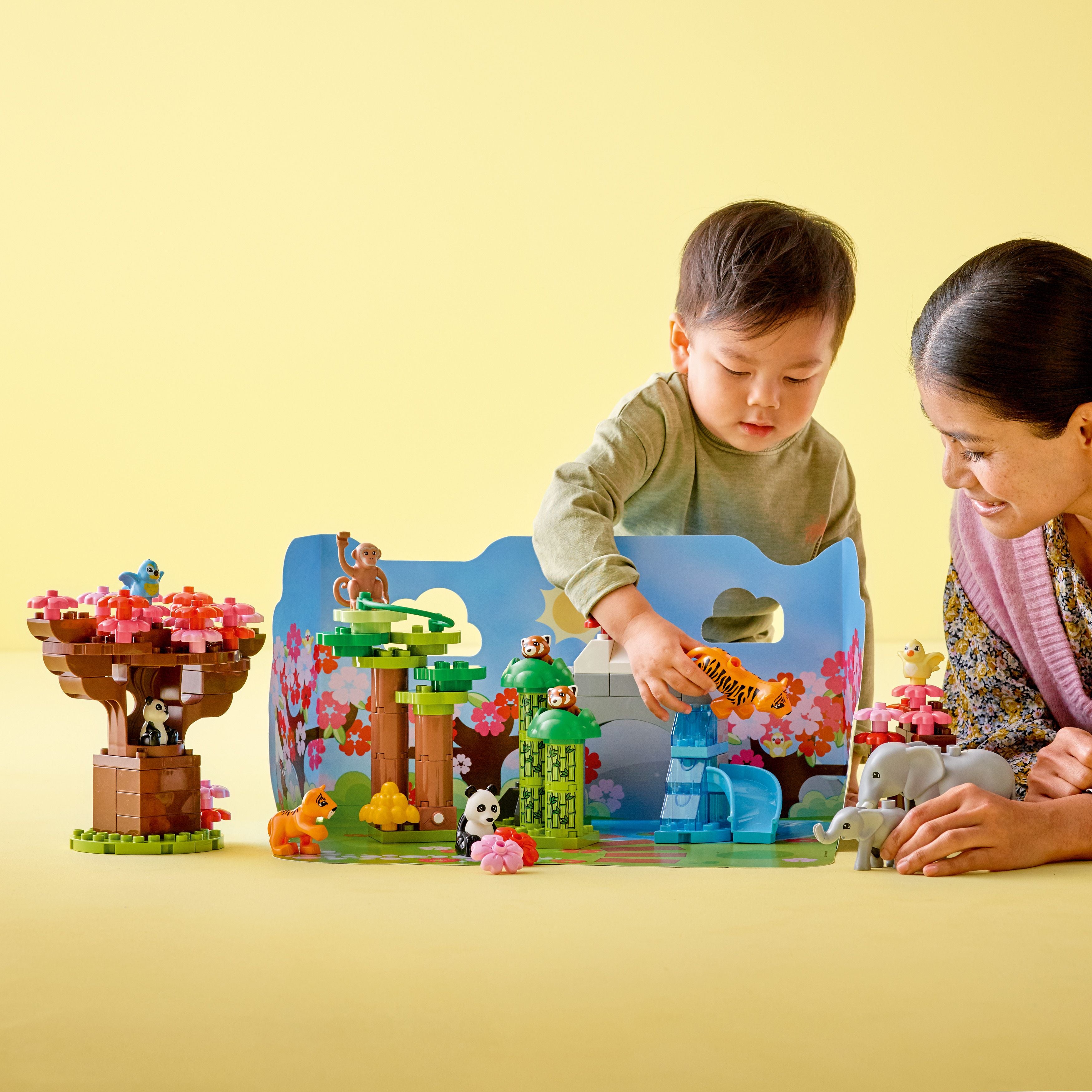 Mutter mit Kind spielt mit aus LEGO duplo Teilen gebautem  Elefant, Panda, Tiger, Pflanzen