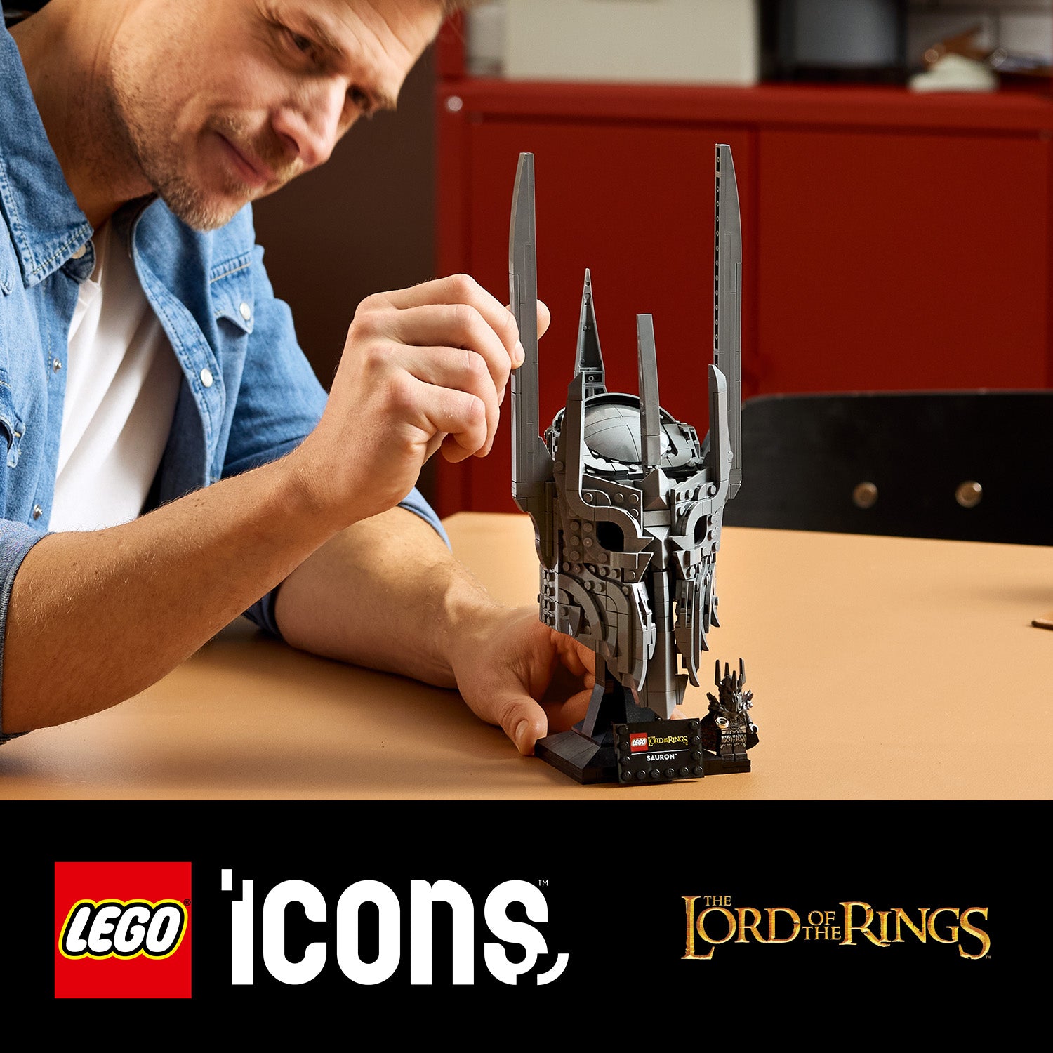 Person baut den LEGO Helm von Sauron aus der Herr-der-Ringe-Reihe auf einem Tisch auf