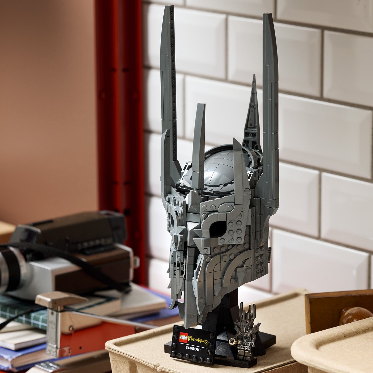 Detailaufnahme des LEGO Sets 'Saurons Helm' aus Der Herr der Ringe mit hohem, spitz zulaufendem Helm auf einem schwarzen Sockel mit Namensschild
