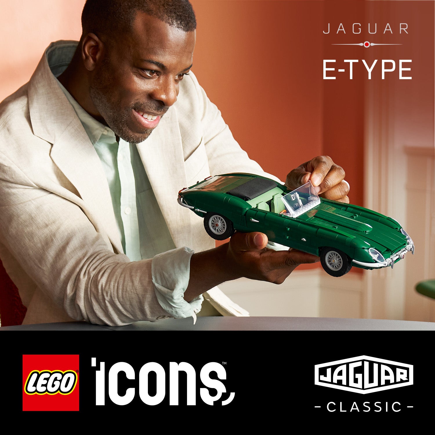 Mann hält grünes LEGO Modell eines Jaguar E-Type und lächelt