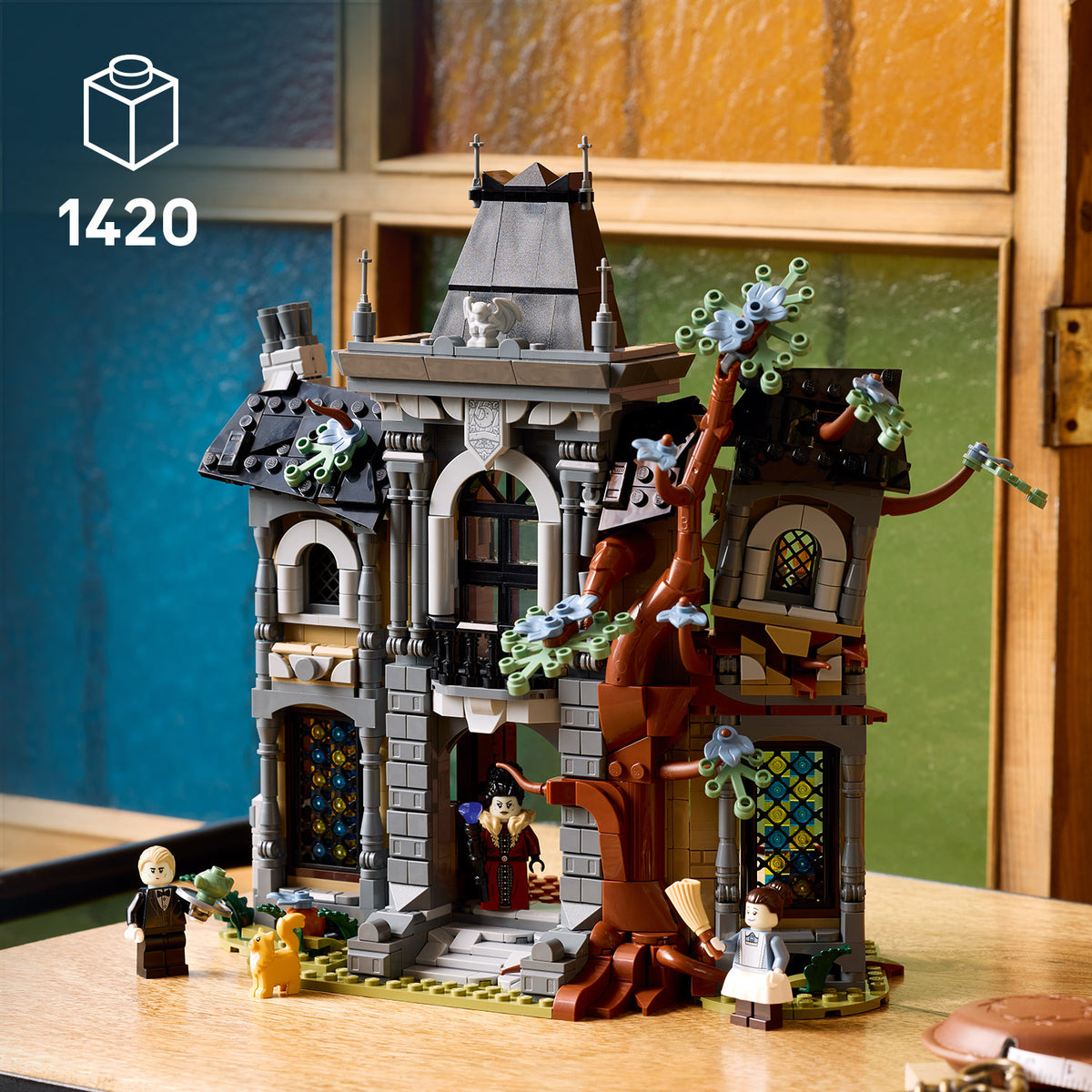 LEGO Modell einer Bürgermeistervilla mit Baum und drei Minifiguren auf einem Tisch vor buntem Hintergrund