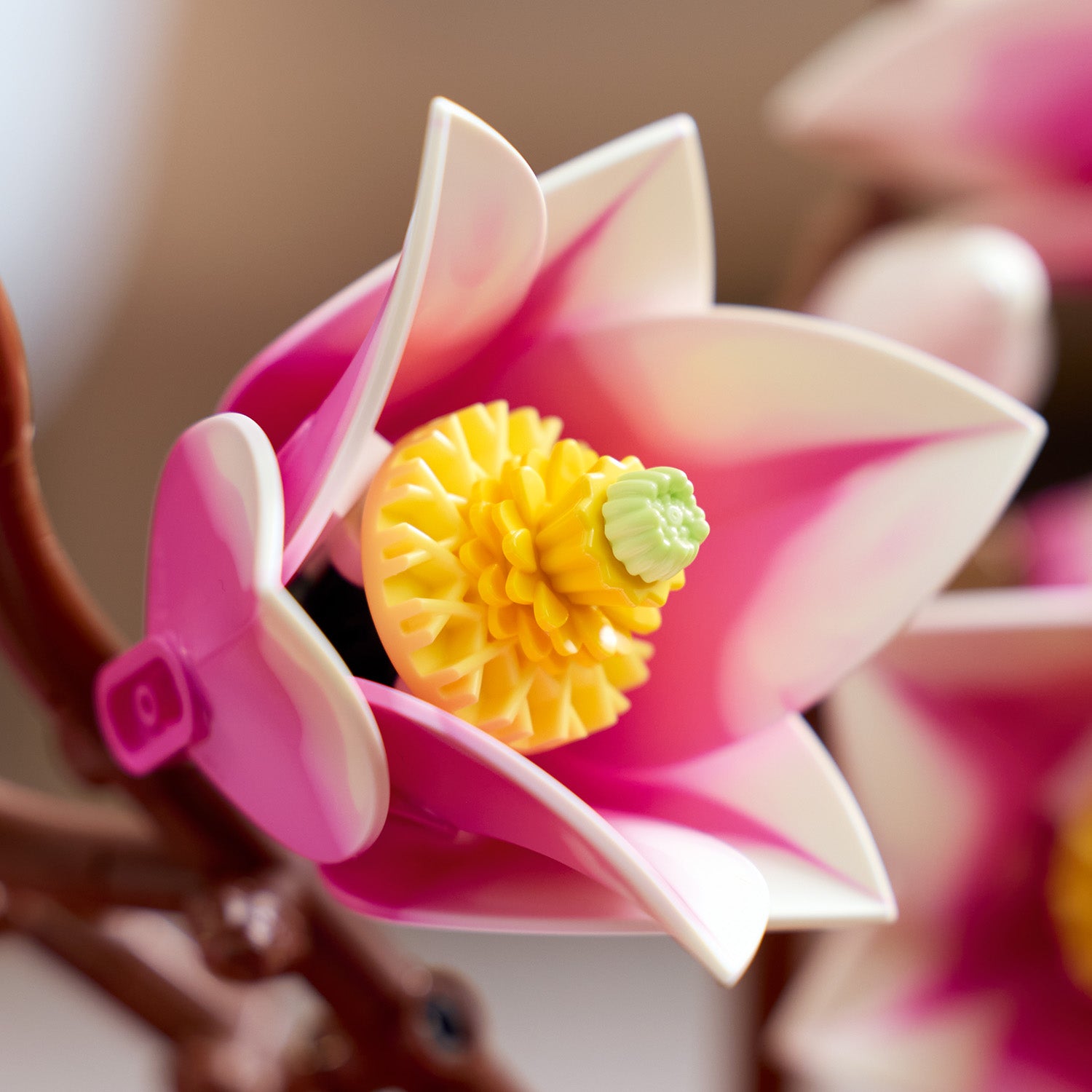 Nahaufnahme eines LEGO Magnolienzweigs mit rosa-weißen Blüten und gelbem Blütenstempel