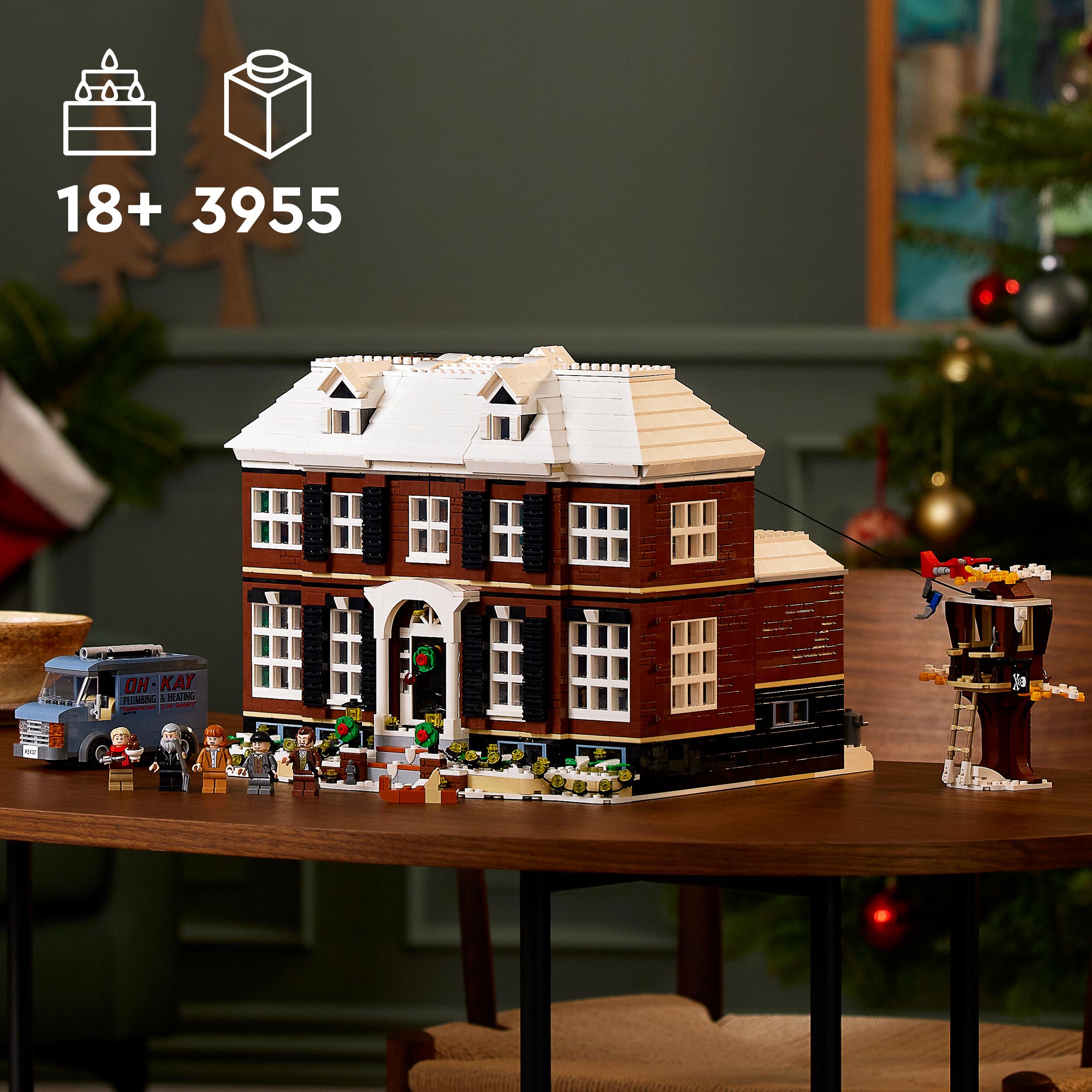 LEGO-Set "Home Alone" mit zweistöckigem Haus, weißem Dach, braunen Wänden, mehreren Fenstern, Weihnachtsdekoration, Minifiguren, Lieferwagen und Baumhaus auf einem Holztisch.