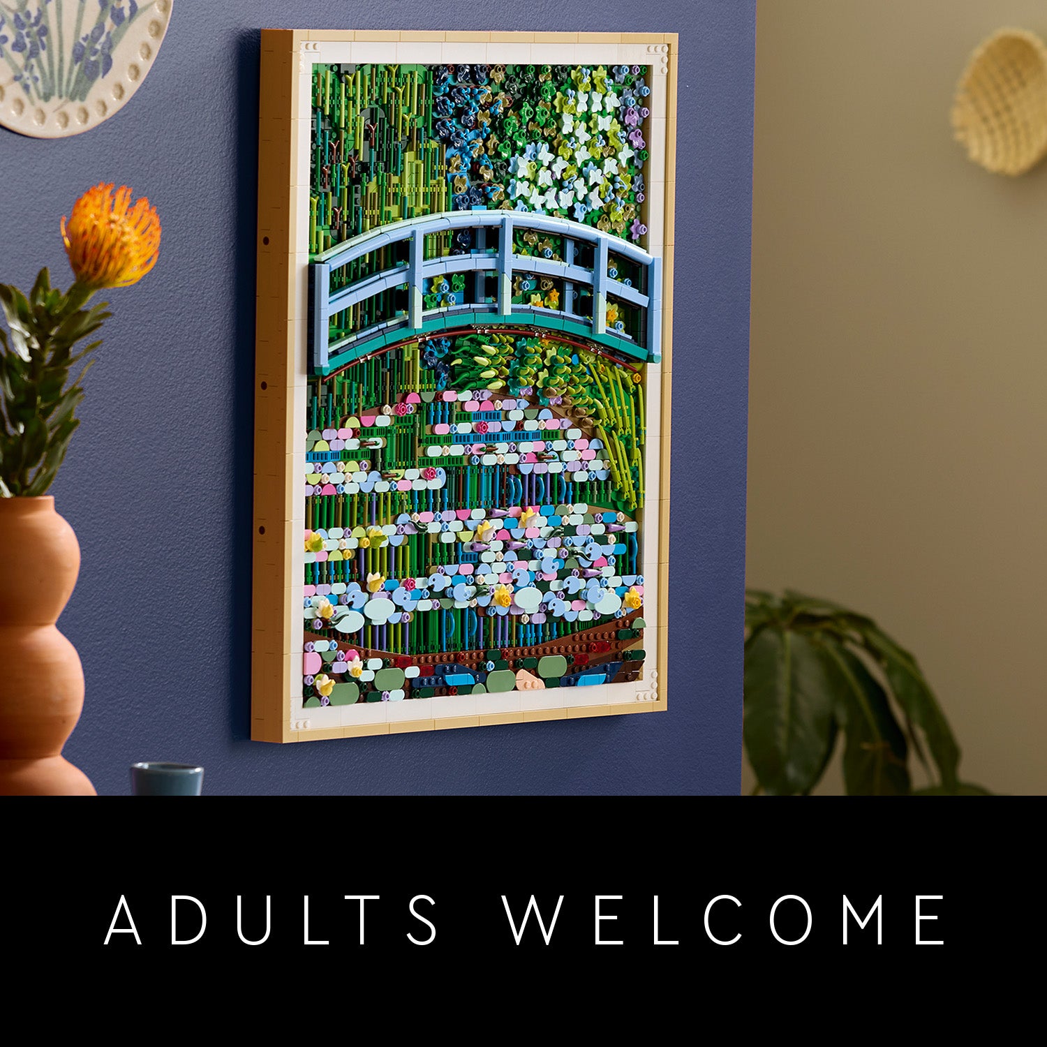 Wandbild aus LEGO Steinen mit einer Brücke über einen Teich, inspiriert von Claude Monets Kunstwerk, an einer blauen Wand mit Pflanzen und Dekorationen im Hintergrund