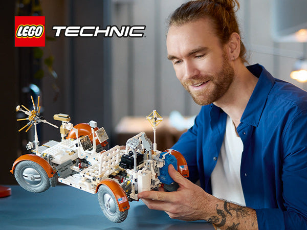 Mann mit blauem Hemd hält ein LEGO Technic Modell des NASA Apollo Lunar Roving Vehicle mit weißen und orangen Bauteilen