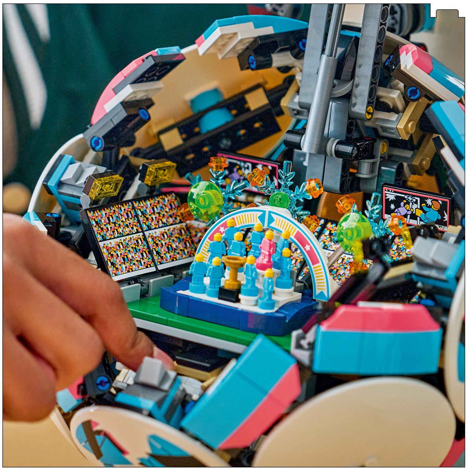Nahaufnahme eines LEGO Sets mit einem Fußballstadion und einer Hand, die an einem Hebel des Sets arbeitet