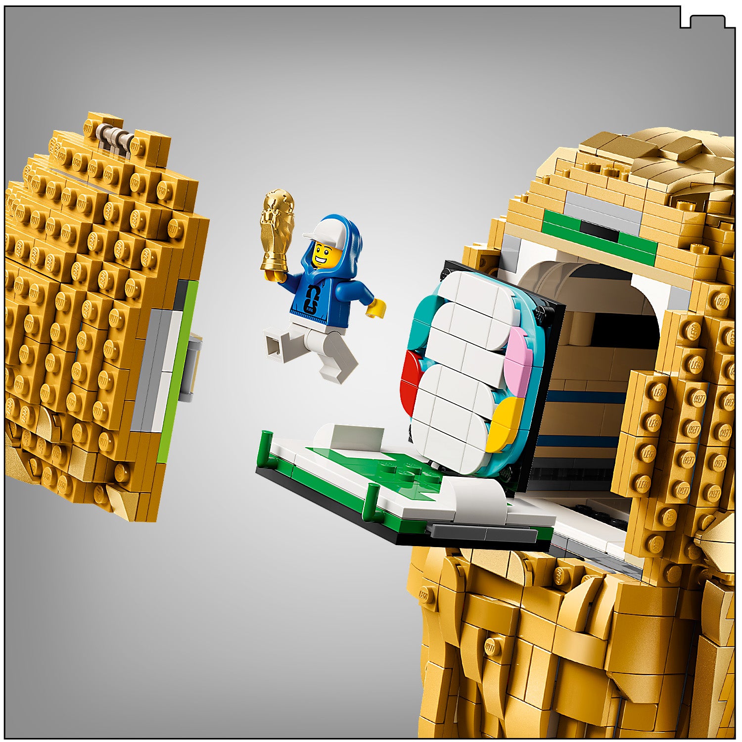LEGO Modell des offiziellen Pokals der FIFA-Fußball-Weltmeisterschaft mit geöffnetem Deckel, aus dem eine Minifigur in blauer Kapuzenjacke springt