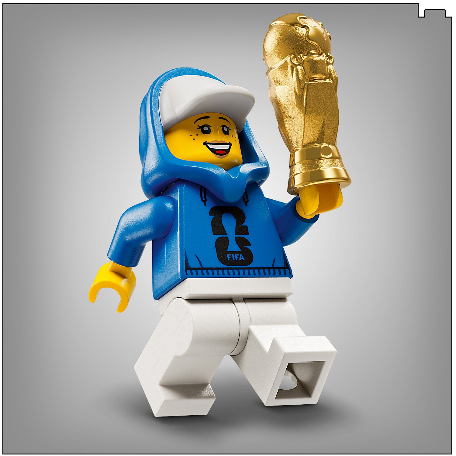 Eine LEGO Figur mit blauer Kapuzenjacke und weißer Mütze hält den goldfarbenen FIFA-Weltmeisterschaftspokal in der rechten Hand