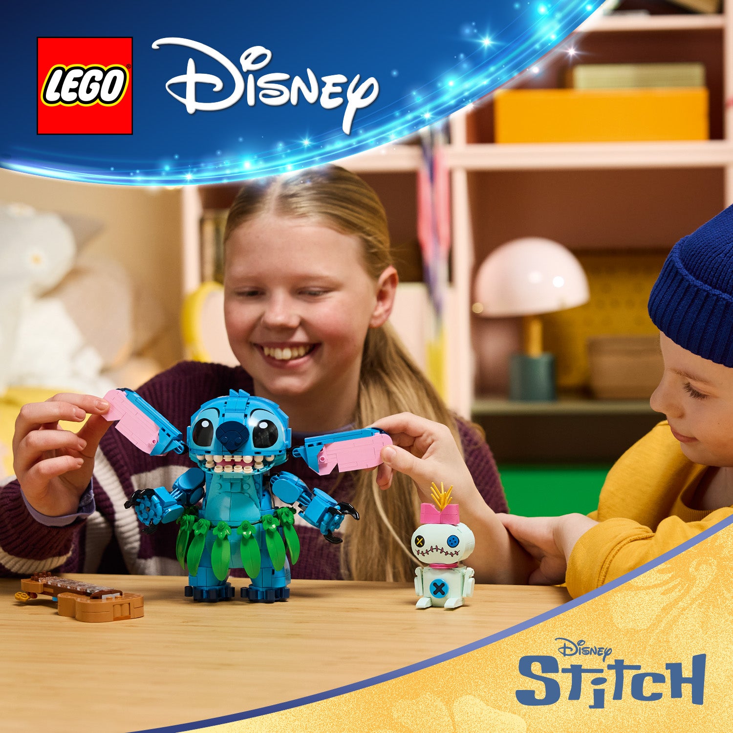 LEGO Disney-Figuren Stitch mit ausgebreiteten Armen und Scrump mit Stachelhaaren auf einem Tisch vor zwei Kindern in einem Zimmer mit Regalen und Lampe