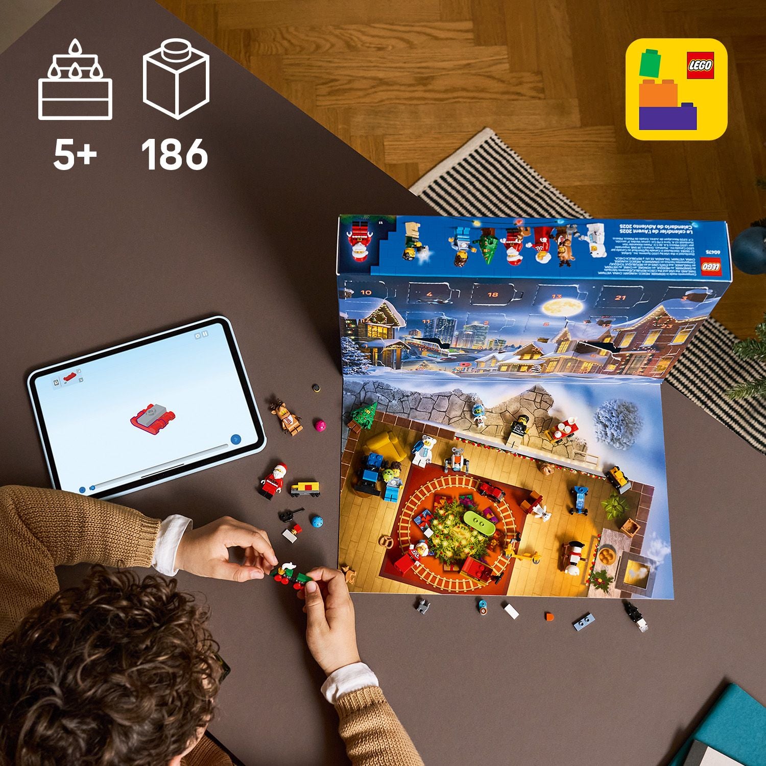 Oben links Altersangabe (5+) und Anzahl Teile (186). Bild von oben, Junge sitzt am Tisch und Spielt mit dem aufgeklappten Kalender. Neben ihm ein Tablet mit einer Bauanleitung drauf