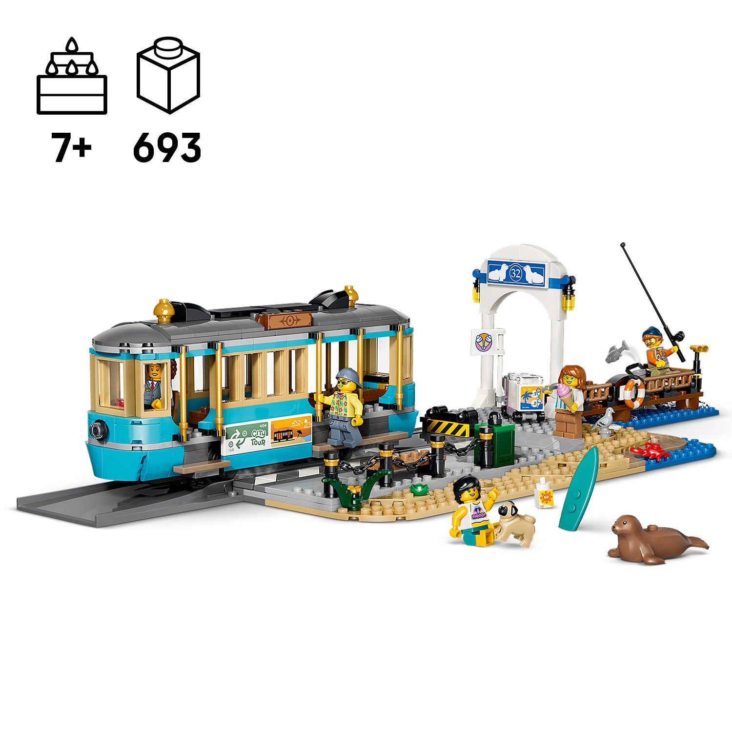 LEGO Set mit einer klassischen Strandbahn auf Schienen, mehreren Minifiguren, einem Angelboot, einem Surfbrett, einem Seehund und einem kleinen Hund auf einem Strandabschnitt mit Haltestelle und Torbogen