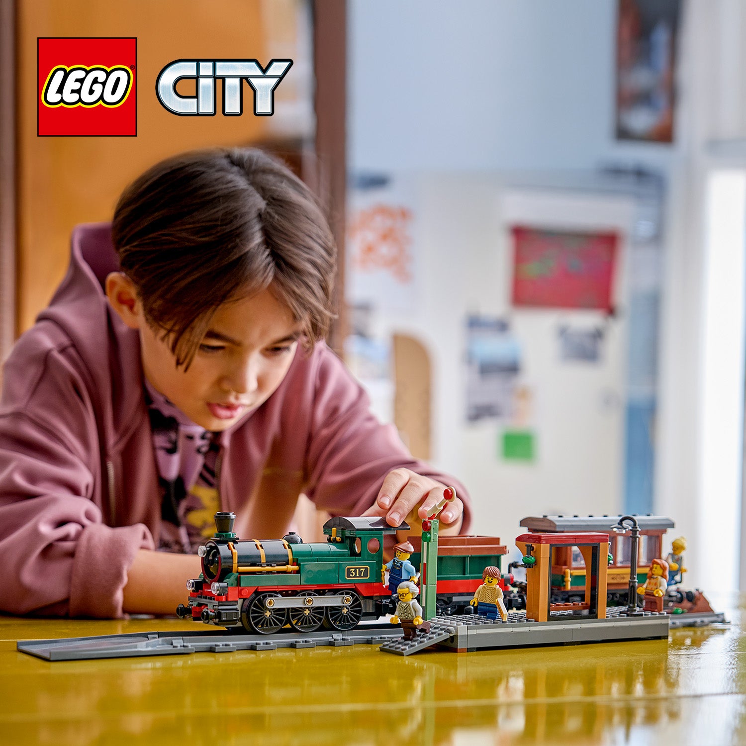 Kind spielt mit einem LEGO City klassischen Dampflokomotivzug mit Schienen und mehreren Minifiguren auf einem Tisch
