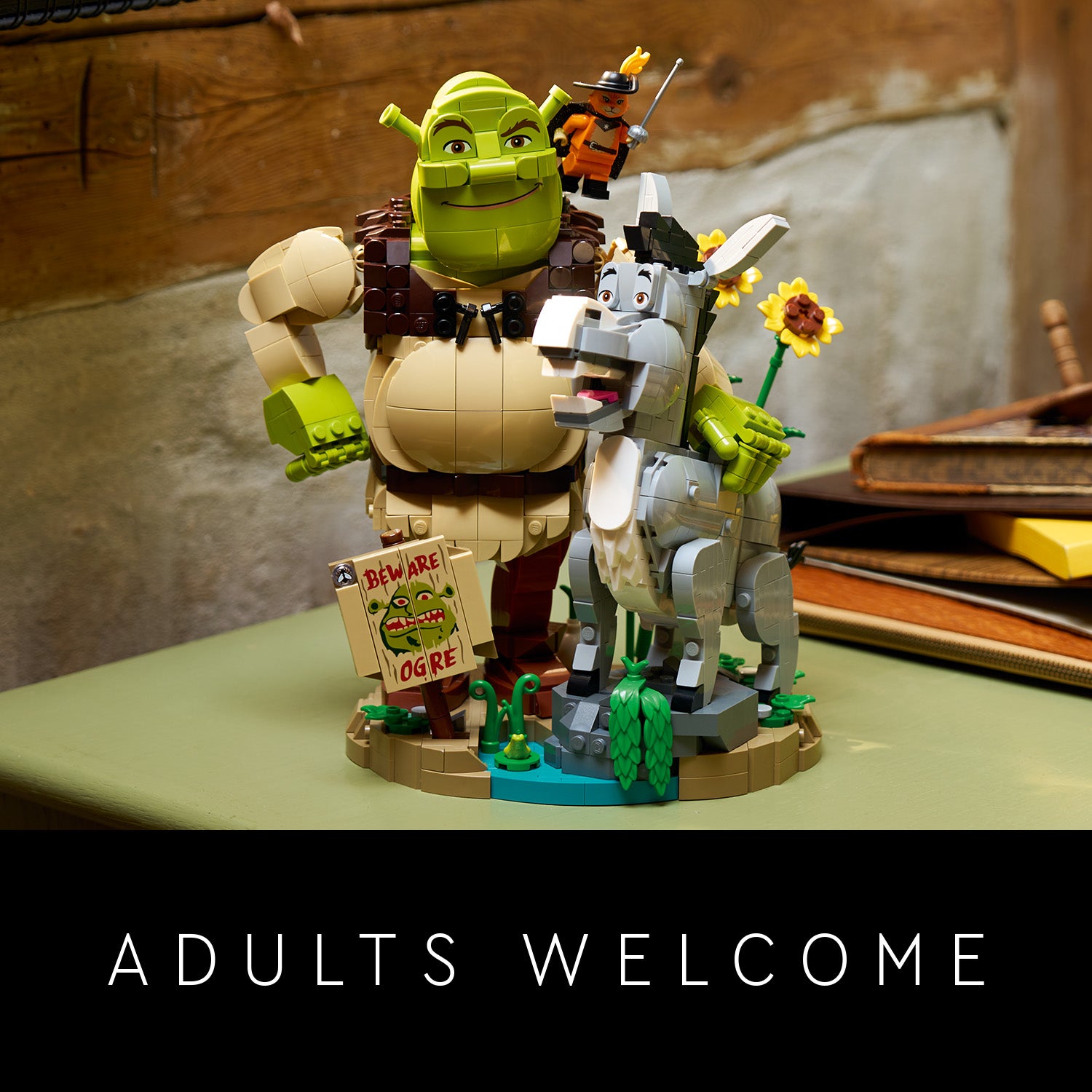 LEGO Figuren von Shrek, Esel und dem gestiefelten Kater auf einem kleinen Diorama mit Schild 'Beware Ogre' und der Aufschrift 'ADULTS WELCOME'