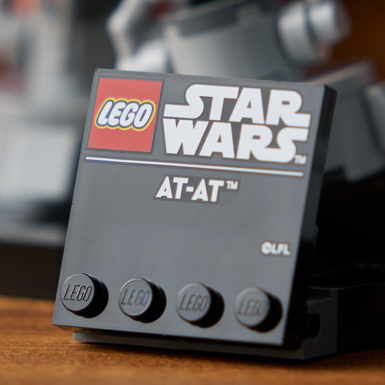 Schwarzes LEGO Schild mit den Logos 'LEGO', 'STAR WARS' und der Bezeichnung 'AT-AT'.
