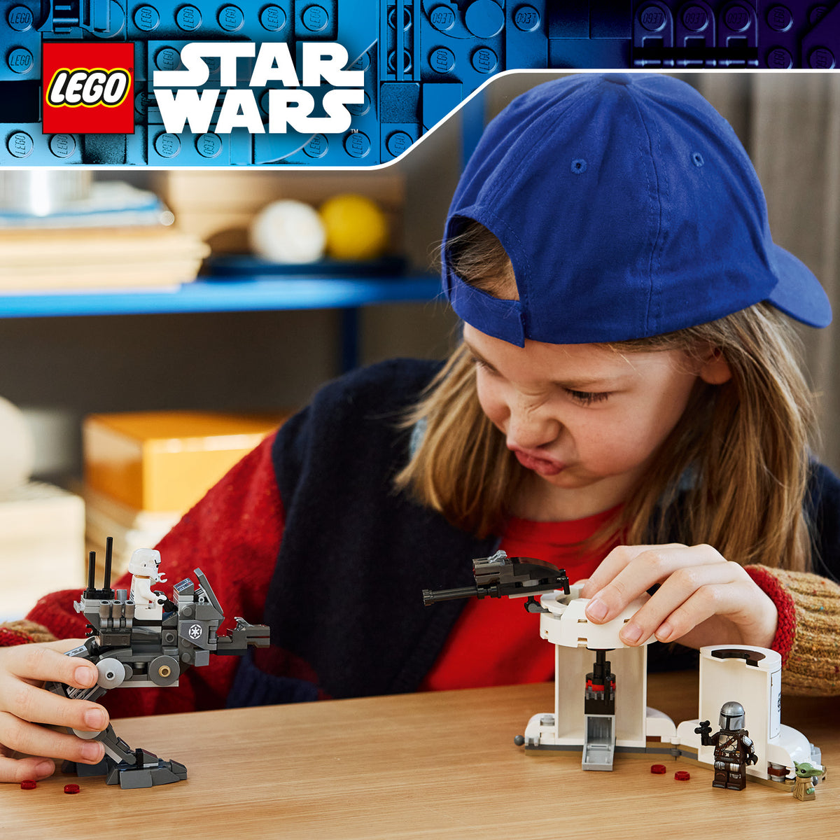 Kind mit blauer Kappe spielt mit LEGO Star Wars Spielzeugfiguren und Fahrzeugen auf einem Holztisch