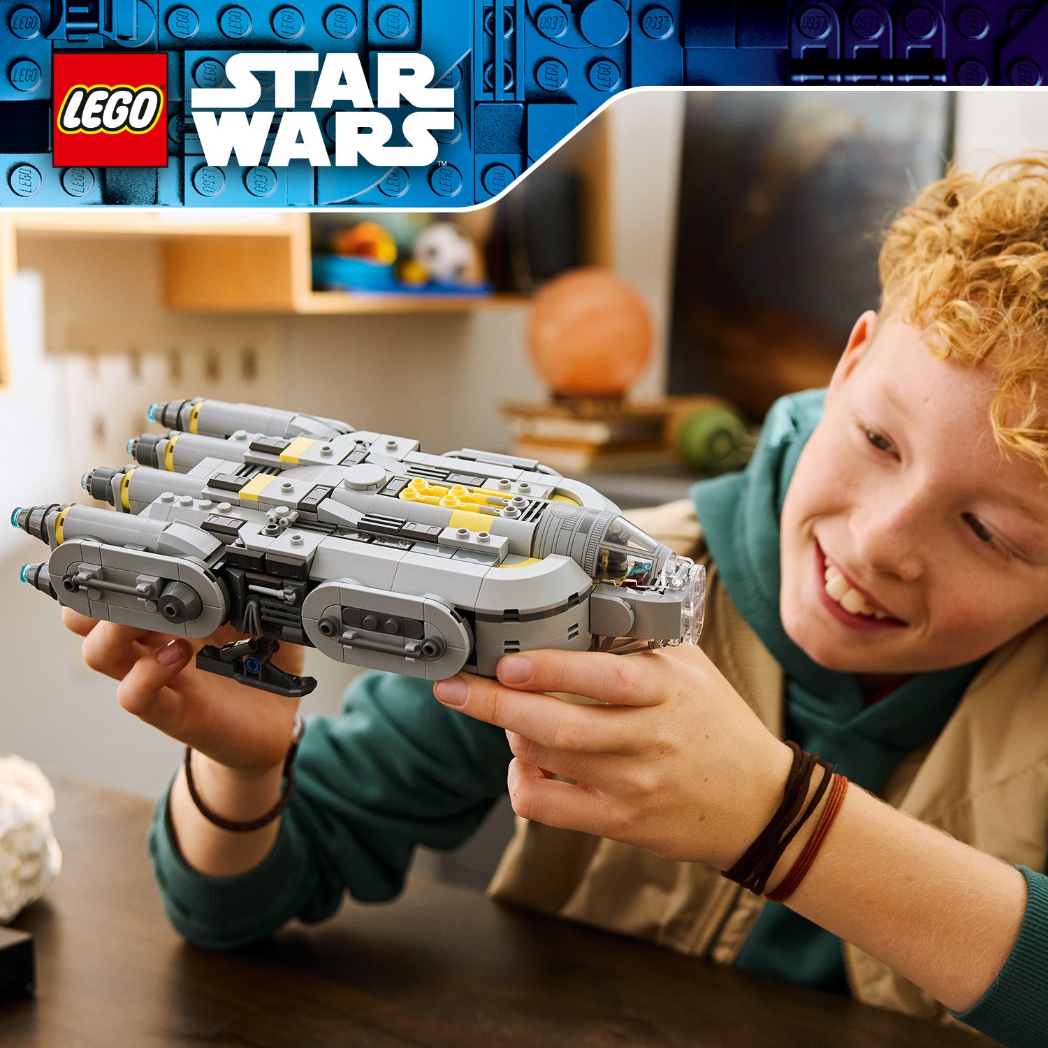 Kind hält ein graues LEGO Star Wars Sternenschiff der Anzellaner mit gelben Details in den Händen