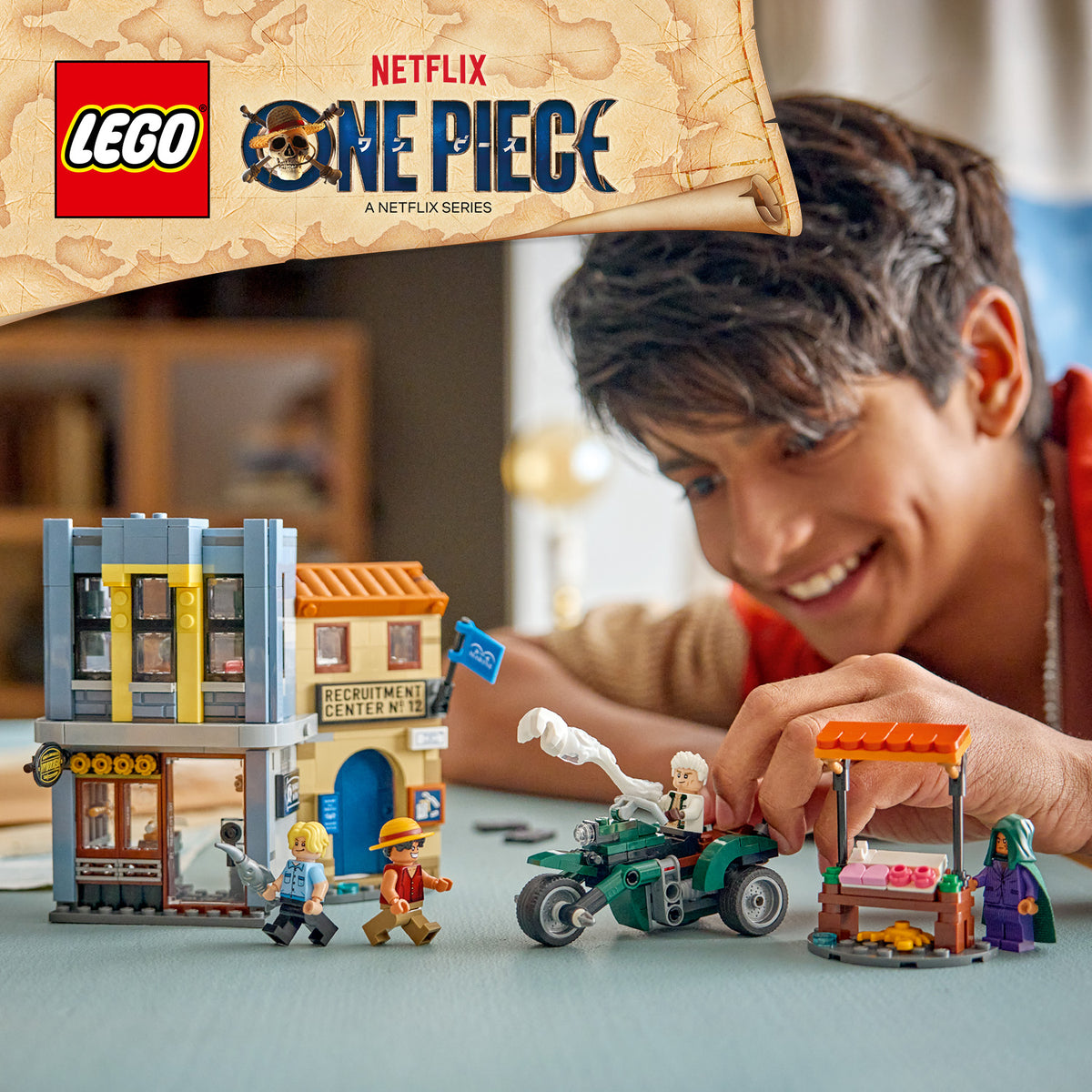 Junge spielt mit LEGO Spielset aus der Serie One Piece mit Gebäuden, Figuren und Fahrzeugen auf einem Tisch.