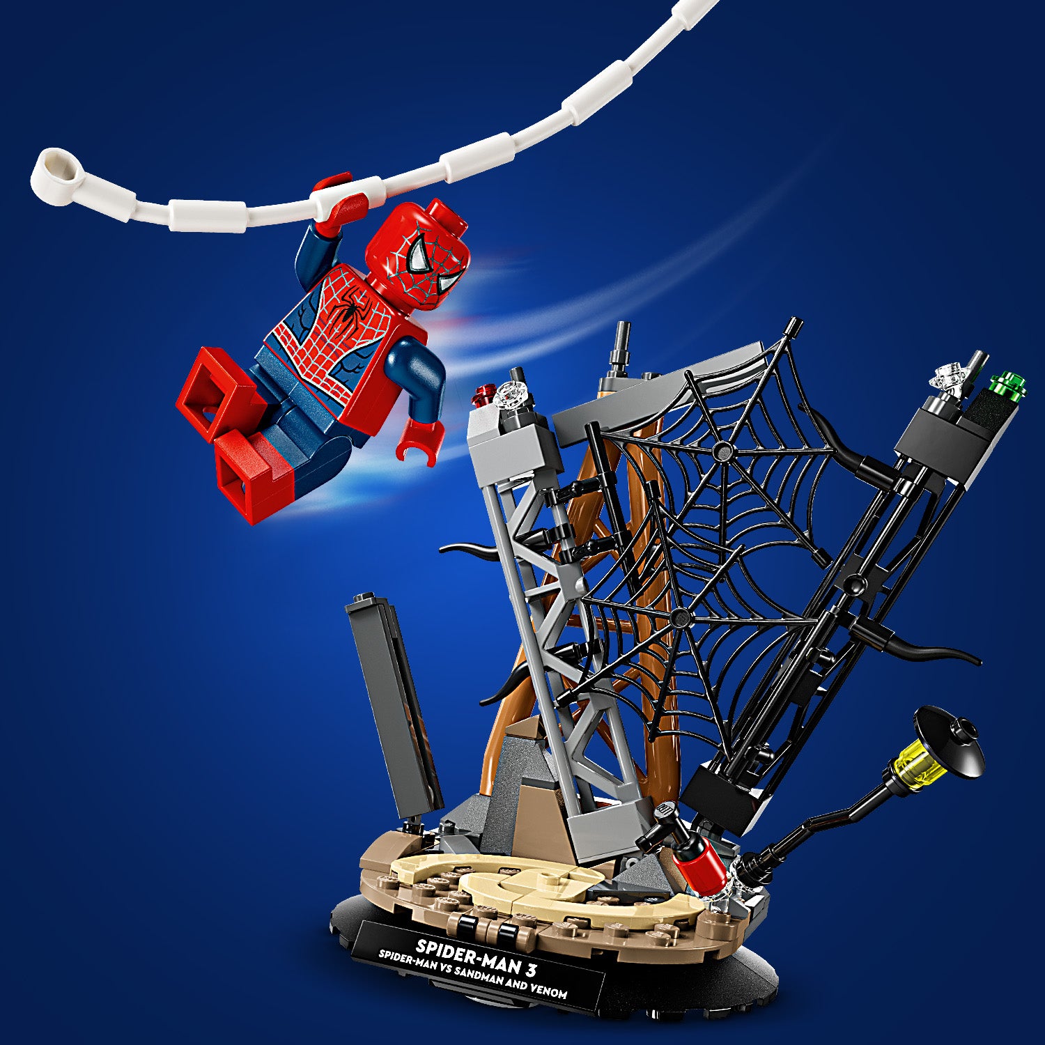 LEGO Spider-Man-Figur schwingt an einem weißen Netzfaden über eine Diorama-Basis mit einem großen schwarzen Spinnennetz und einem Laternenpfahl.