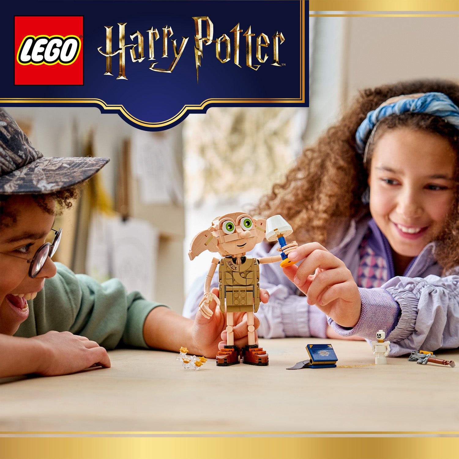 Zwei Kinder spielen mit einer LEGO Harry Potter Dobby-Figur und Zubehör auf einem Tisch