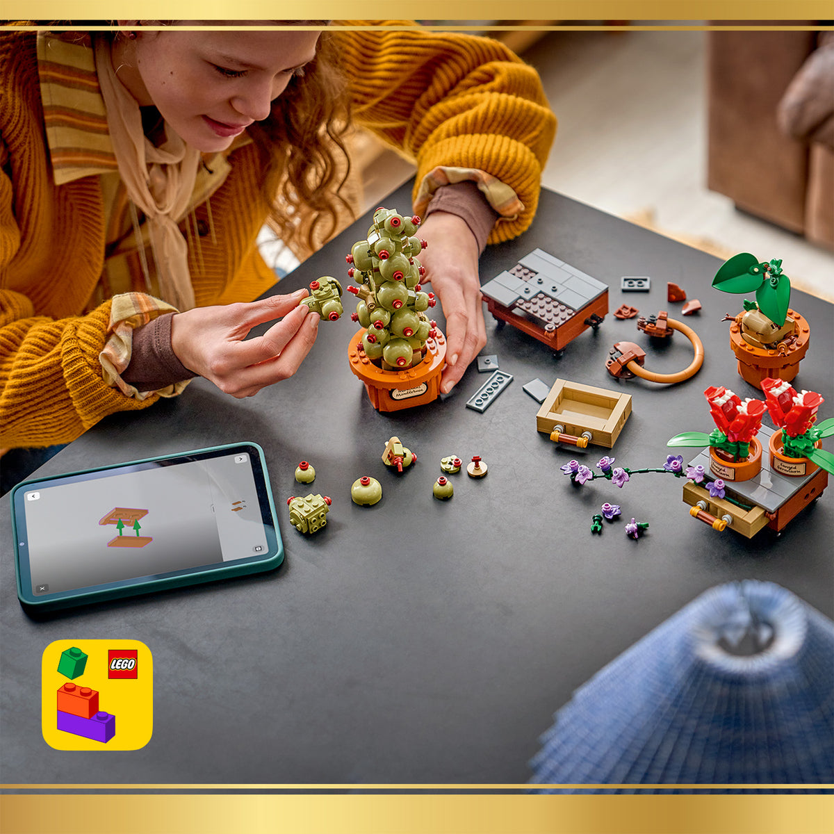 Kind baut mit LEGO Steinen verschiedene Pflanzenmodelle auf einem Tisch, daneben liegt ein Tablet mit Bauanleitung