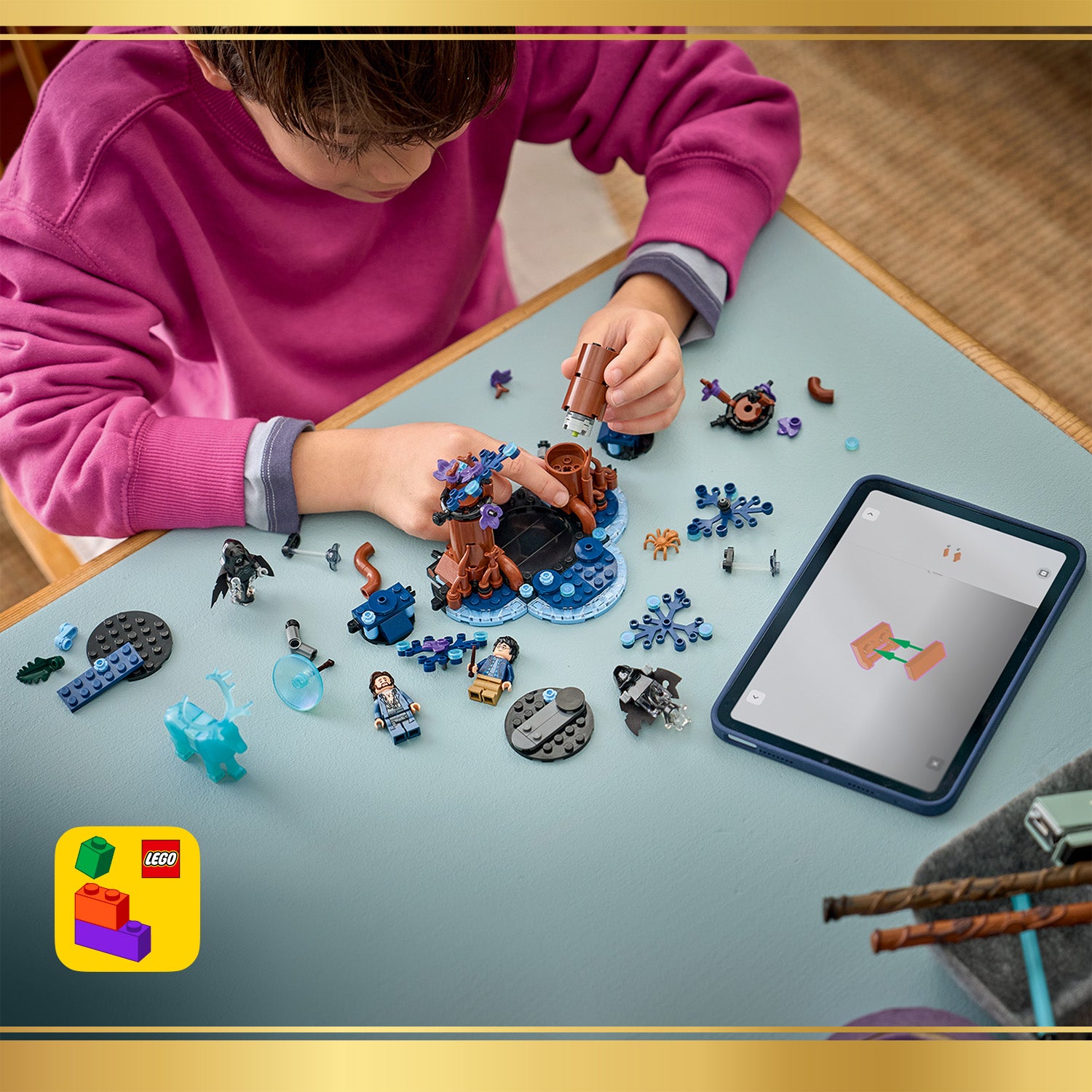 Kind baut LEGO Set mit Figuren und Bauteilen auf einem Tisch neben einem Tablet mit Bauanleitung