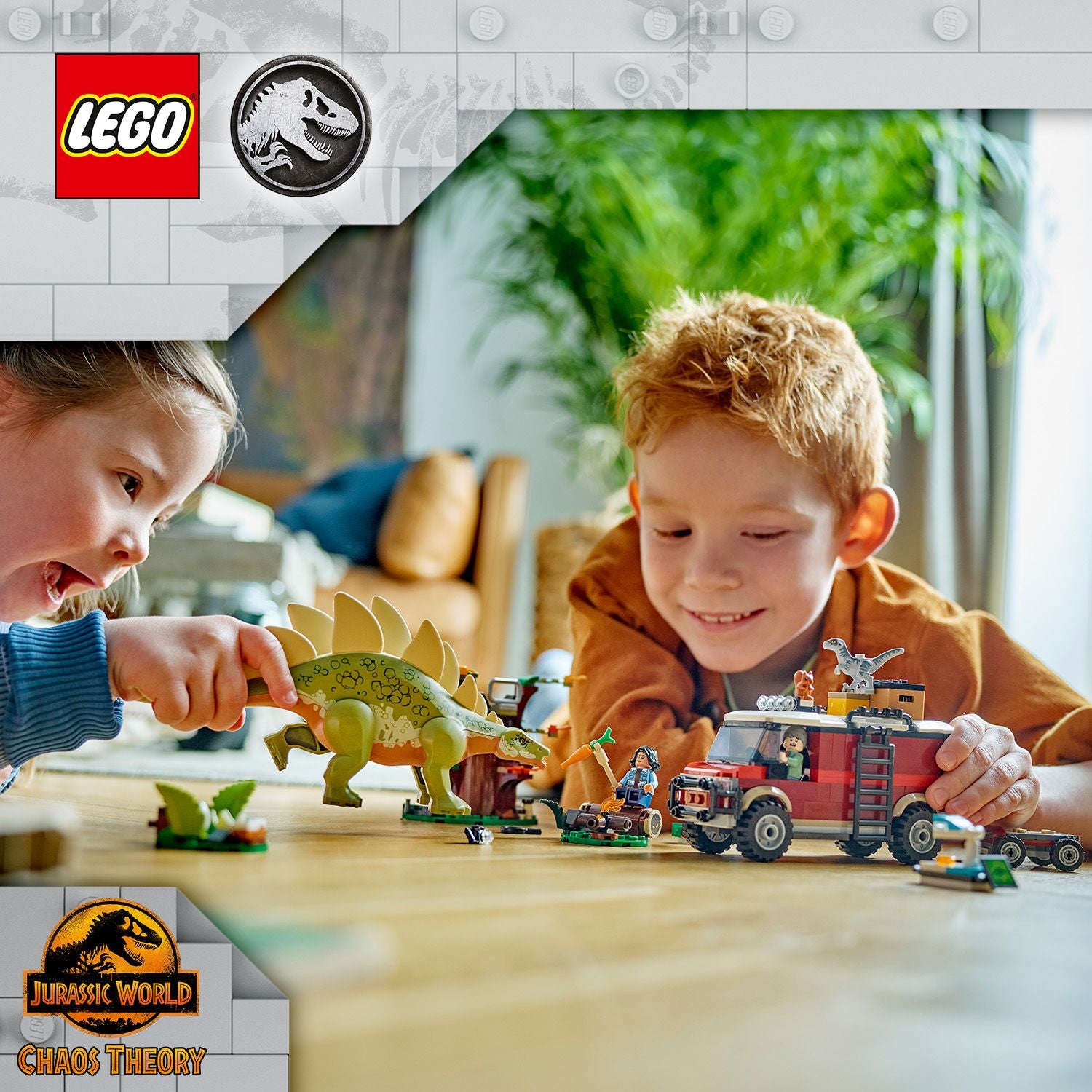 Zwei Kinder spielen mit LEGO Jurassic World Set, darunter ein grüner Stegosaurus und ein rotes Fahrzeug mit Figuren und Zubehör auf einem Holztisch.