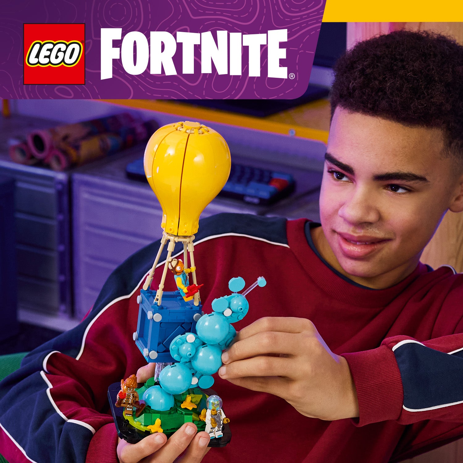 Kind hält LEGO Fortnite Spielset mit Heißluftballon, blauer Raupe und Minifiguren in Händen
