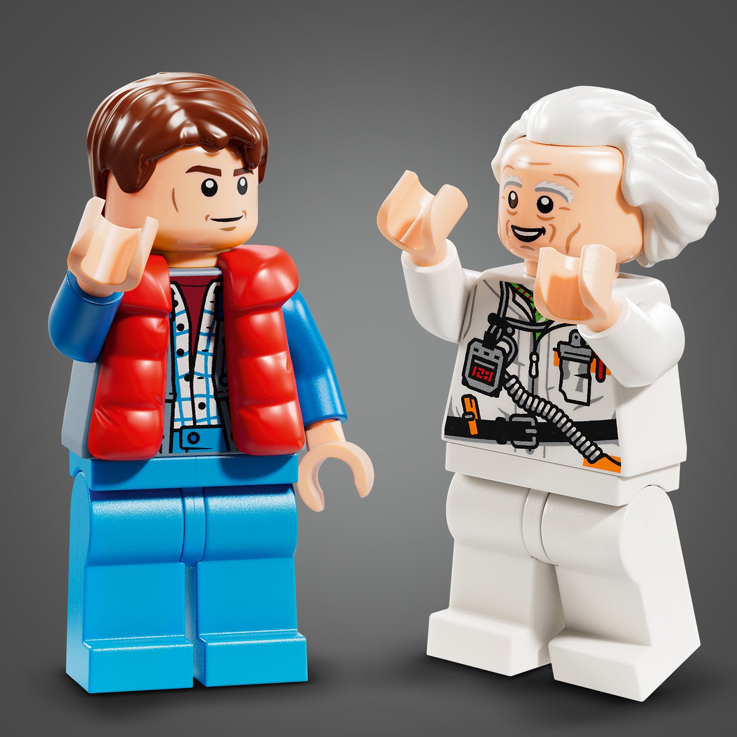Zwei LEGO Minifiguren aus dem Set Speed Champion: eine mit roter Weste und braunen Haaren, die andere mit weißem Haar und weißem Overall mit technischen Details.