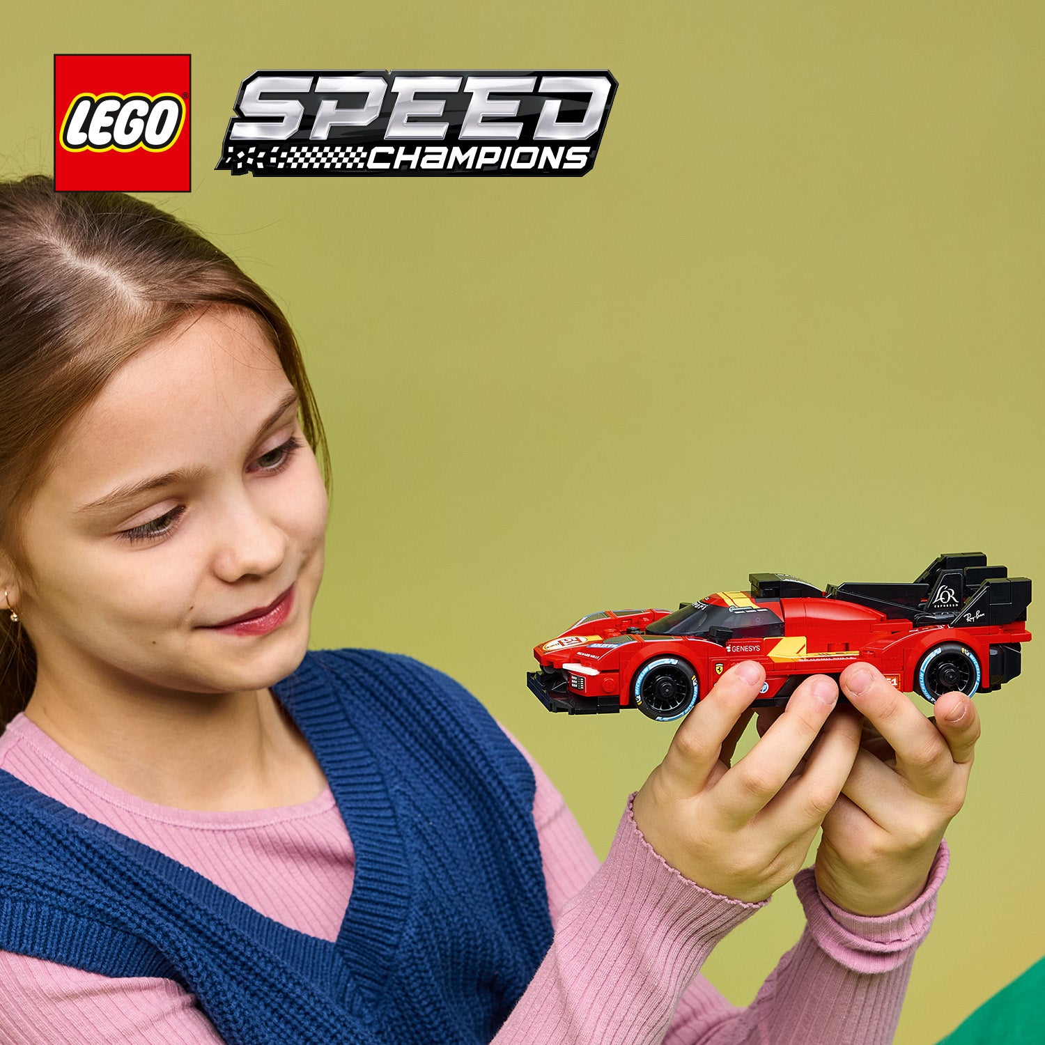 Kind hält ein rotes LEGO Speed Champions Modell des Ferrari 499P Rennautos vor grünem Hintergrund