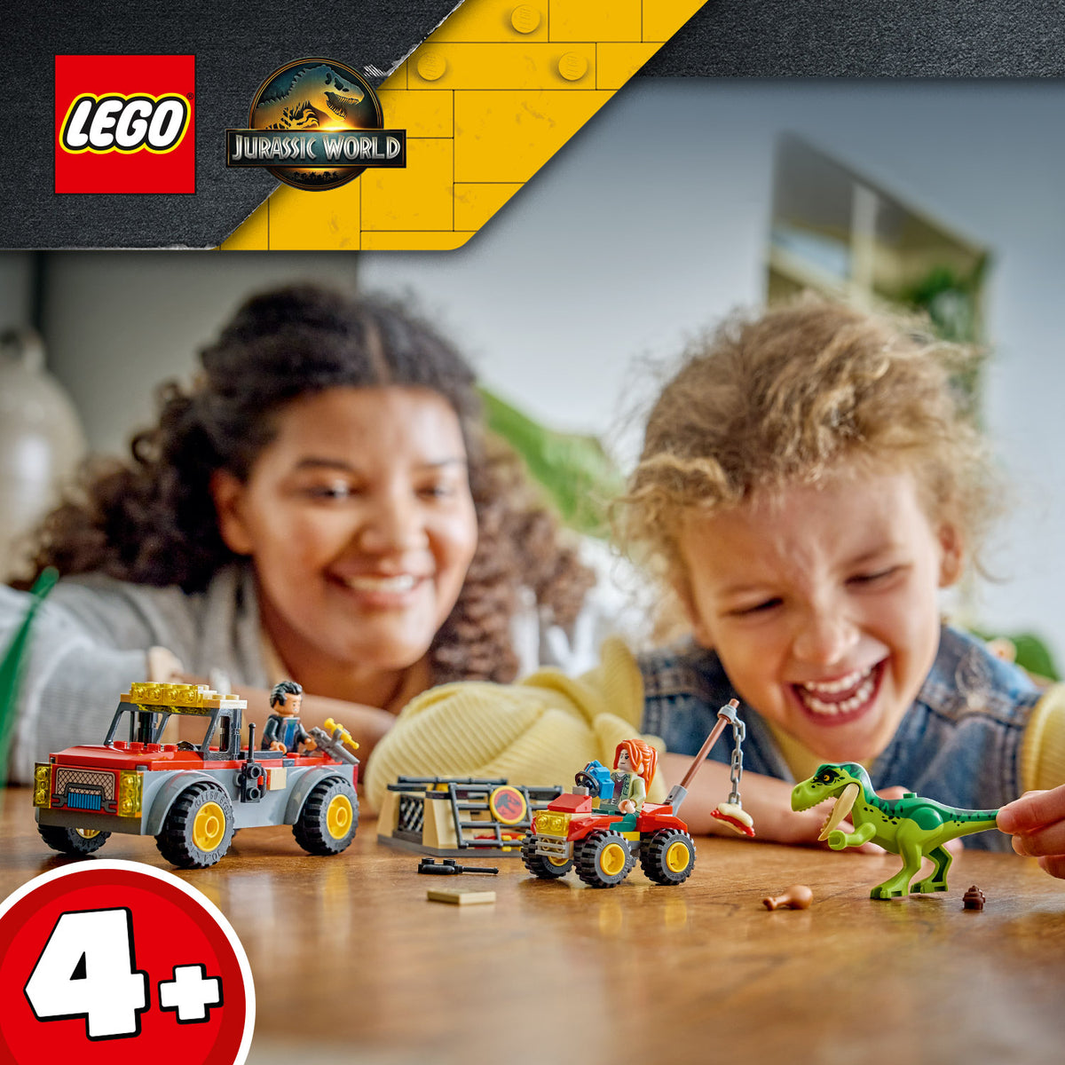 Zwei Kinder spielen mit LEGO Jurassic World Fahrzeugen und einer Dinosaurierfigur auf einem Holztisch